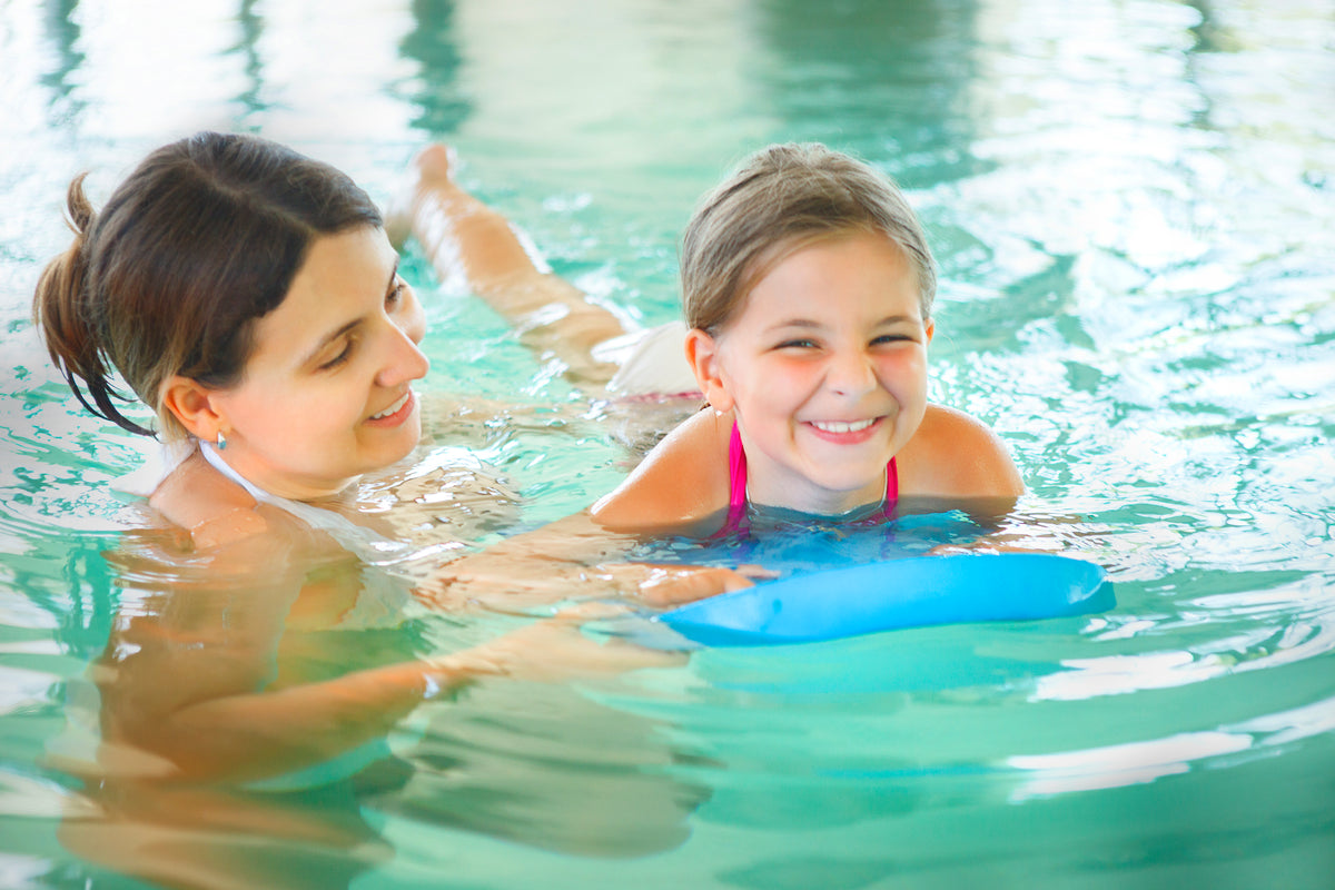 Mutter übt mit ihrer Tochter im Schwimmbad